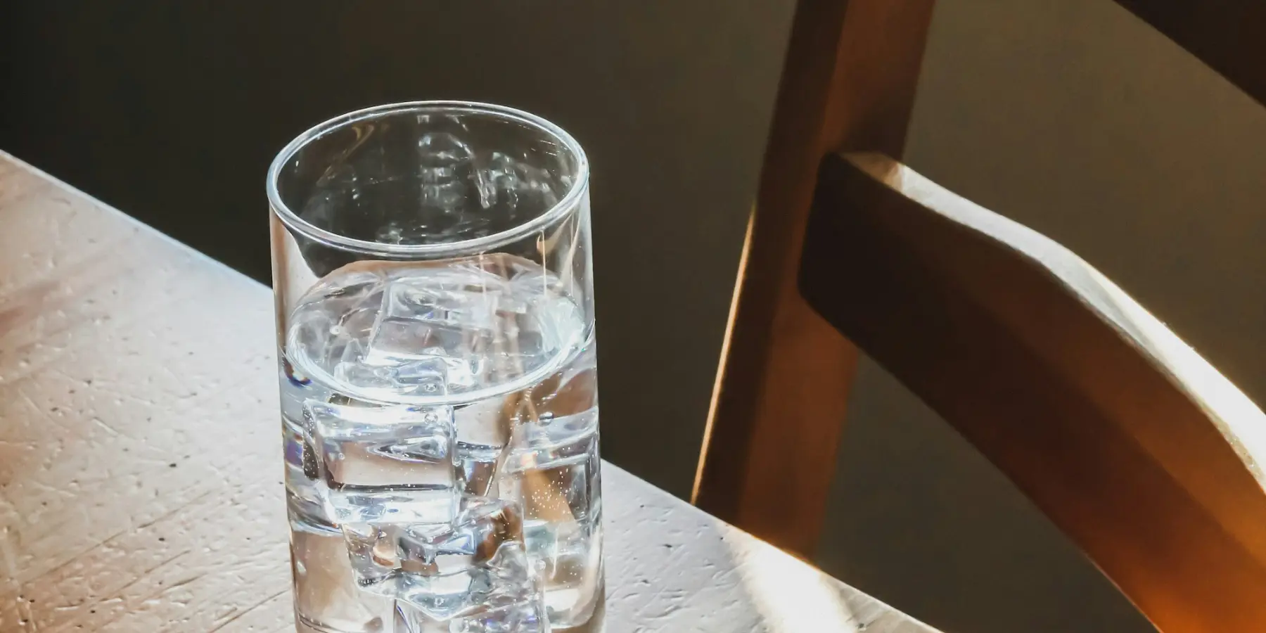 Verre d'eau sur une table en bois, dans la lumière du matin